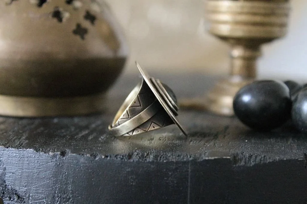 Bague La Magma en laiton gravé sertie d'ivoire végétal carbonisé, vue de profil, posée sur ardoise - Seeds Créations artisanales