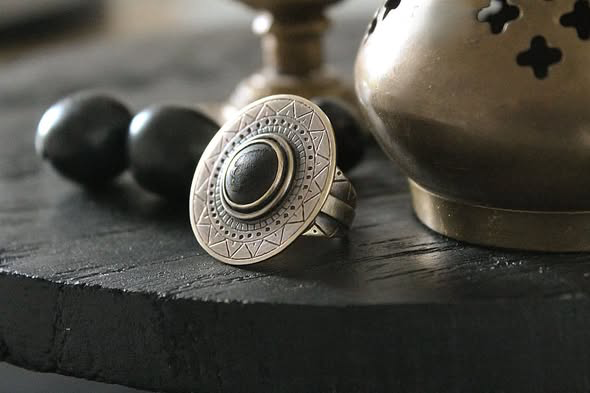 Bague La Magma en laiton gravé sertie d'ivoire végétal carbonisé posée sur ardoise - Seeds Créations artisanales