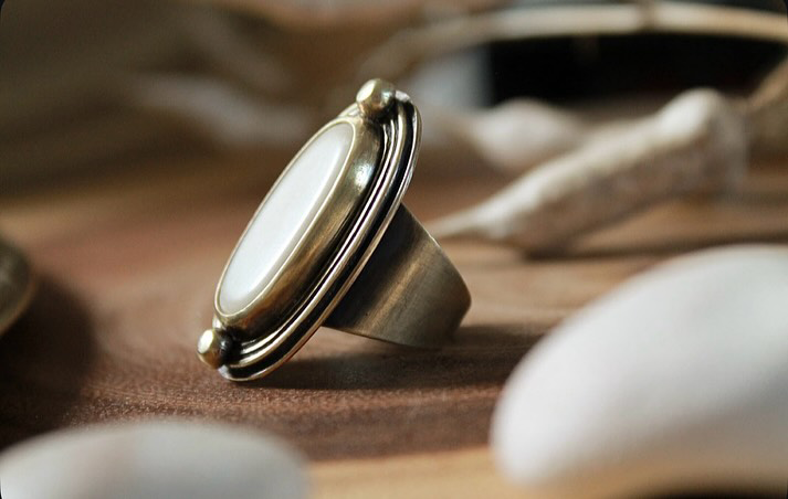 Bague La Taguaba en laiton et cabochon d'ivoire végétal taillé et poli posée sur bois - Seeds Créations artisanales