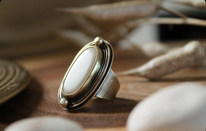 Bague La Taguaba en laiton et cabochon d'ivoire végétal taillé et poli posée sur bois - Seeds Créations artisanales